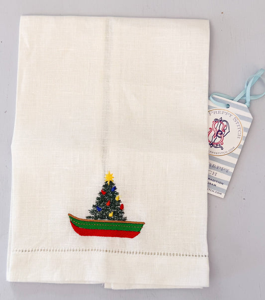 White towel with embroidered Christmas tree design on a gray background
